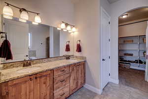 Bathroom with a spacious closet, double vanity, a bathtub, light colored carpet, and light tile patterned floors