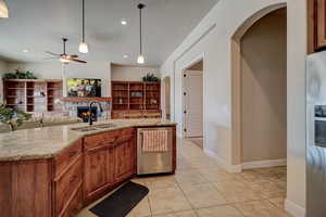 Kitchen featuring wood finish cabinets, arched walkways, a stone fireplace, light stone countertops, and a textured ceiling