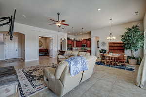 Living room featuring arched walkways, light tile patterned floors, a chandelier, and ceiling fan