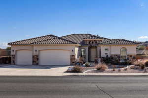 Mediterranean / spanish house featuring stone siding, stucco siding, driveway, and an attached garage