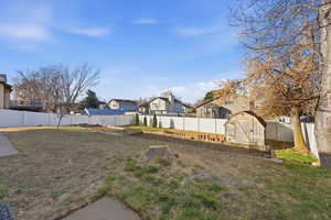Fenced backyard with a storage unit and a residential view