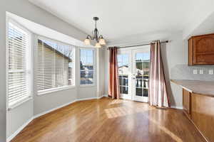 Unfurnished dining area featuring french doors, light wood-style floors, and suspended lighting
