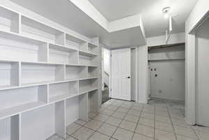 Laundry room featuring a textured ceiling and light tile patterned floors