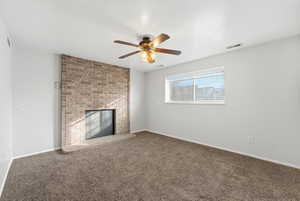 Unfurnished living room with carpet, a ceiling fan, a fireplace, and a textured ceiling