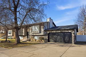 View of front facade featuring concrete driveway, a garage, and a chimney
