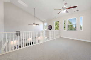 Empty room with vaulted ceiling, carpet floors, and a ceiling fan
