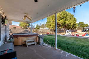 Fenced backyard featuring a patio, ceiling fan, and a hot tub