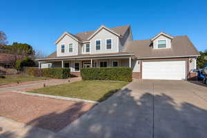 View of front of home with driveway, covered porch, a front lawn, and brick siding