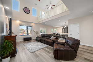 Living area featuring recessed lighting, ceiling fan, light wood-style floors, and a high ceiling
