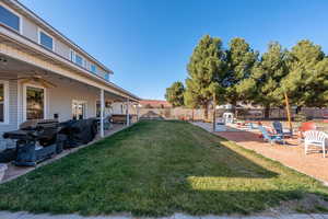 Fenced backyard with a patio area, ceiling fan, and a hot tub