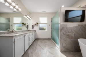 Full bathroom with a freestanding tub, double vanity, and a stall shower