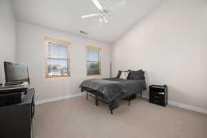 Bedroom featuring light carpet, vaulted ceiling, and a ceiling fan