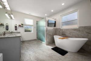 Full bath with vanity, a stall shower, a soaking tub, tile walls, and recessed lighting