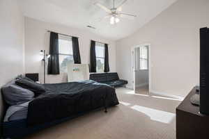 Bedroom with vaulted ceiling, carpet flooring, a ceiling fan, and multiple windows