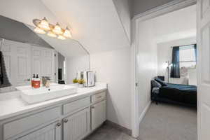Bathroom featuring vanity, vaulted ceiling, and dark carpet