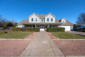 View of front facade featuring a front lawn, concrete driveway, and covered porch