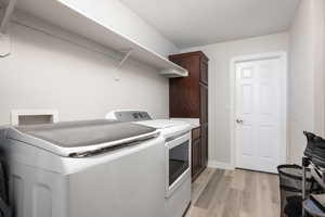 Laundry area featuring cabinet space, light wood-style floors, and washing machine and clothes dryer