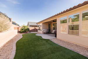 Fenced backyard with a ceiling fan and a patio