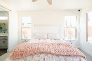 Bedroom featuring light carpet, ensuite bathroom, multiple windows, and ceiling fan