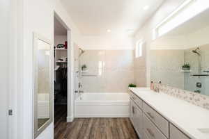 Full bathroom featuring a walk in closet, double vanity, dark wood-style flooring, bathing tub / shower combination, and recessed lighting