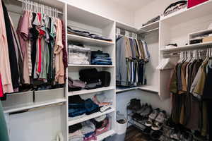 Walk in closet with dark wood-style floors