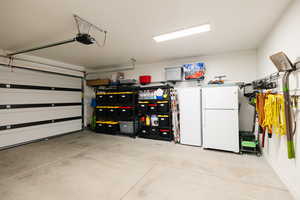 Garage featuring freestanding refrigerator and a garage door opener