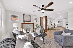 Living area featuring wood finished floors, a brick fireplace, recessed lighting, and a ceiling fan