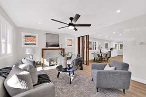 Living area with light wood-style flooring, a fireplace, ceiling fan, and recessed lighting