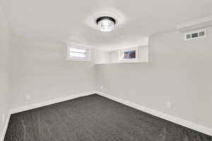 Below grade area with dark carpet and baseboards