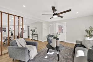 Living room with light wood-style floors, a ceiling fan, and recessed lighting