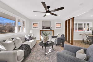 Living room featuring ceiling fan, light wood-style flooring, recessed lighting, and a fireplace