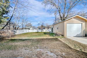 View of yard featuring an outdoor structure, a garage, and driveway