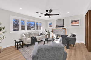 Living area with a ceiling fan, a brick fireplace, light wood finished floors, and recessed lighting