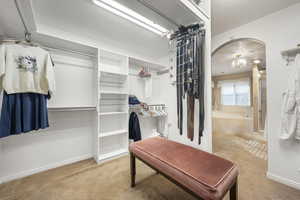Walk in closet with arched walkways and light carpet