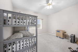 Carpeted bedroom with a ceiling fan and baseboards