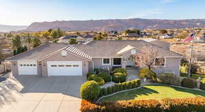 Ranch-style home featuring a garage, concrete driveway, a front yard, a mountain view, and stucco siding