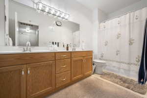 Bathroom featuring double vanity and shower / bath combination with curtain