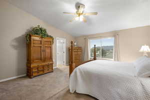 Bedroom with lofted ceiling, light carpet, and a ceiling fan