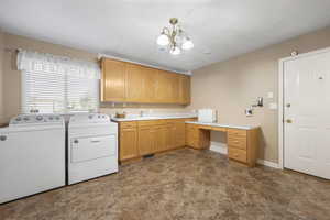 Laundry area featuring separate washer and dryer, cabinet space, hanging lights, and a desk