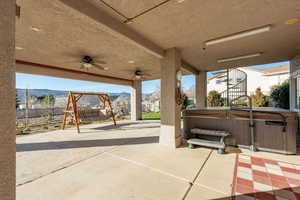 Fenced backyard featuring a hot tub, a patio, a ceiling fan, and a mountain view