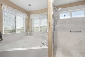Full bath with a marble finish shower and a jetted tub
