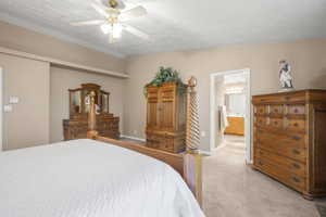 Bedroom featuring light carpet, ceiling fan, and ensuite bath