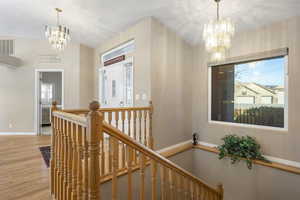 Hallway with a chandelier, an upstairs landing, and light wood-style flooring