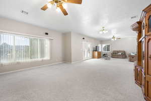 Unfurnished living room with a ceiling fan, carpet floors, and suspended lighting