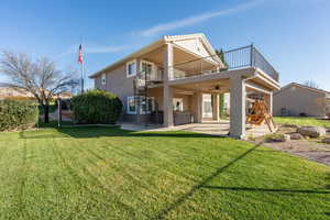 Rear view of house featuring a patio, a lawn, a hot tub, and stucco siding