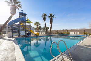 Community pool featuring a water slide and a patio