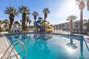Community pool with a patio area and a water slide