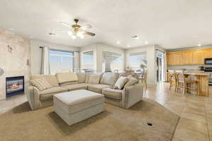 Living room with a tile fireplace, recessed lighting, a ceiling fan, light tile patterned floors, and a textured ceiling