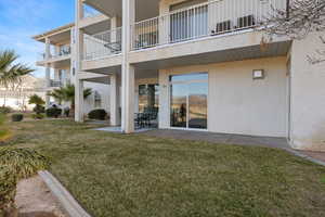 Back of house featuring stucco siding, a yard, and a patio