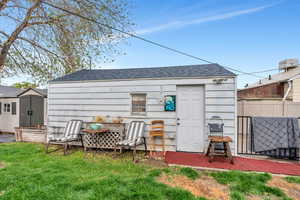 Back of property with a shingled roof and a storage shed
